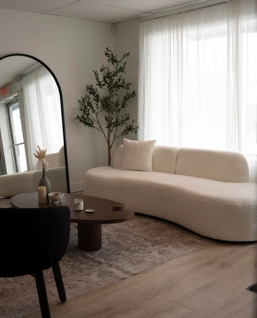 Salle d'accueil de la Clinique NSKIN, avec son divan blanc et son grand miroir arqué