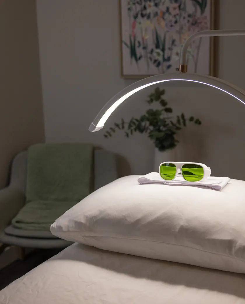Lunettes de protection posées sur l'oreiller de la table de soin, sous la lampe en arc de la Clinique NSKIN