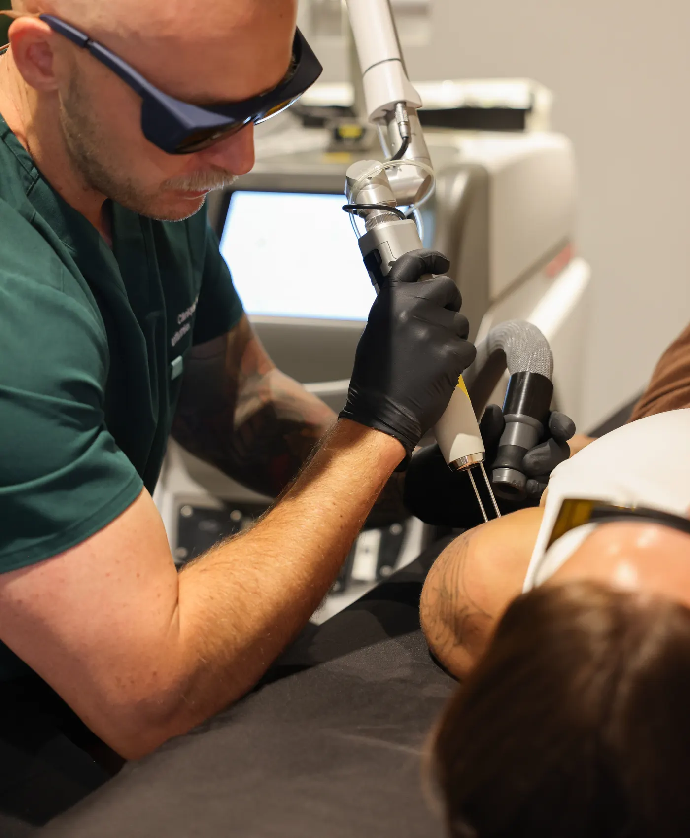 Ricardo, infirmier de la Clinique NSKIN, en lunettes de protection et gants, traitant un tatouage au laser Quanta Q-Plus C Evo