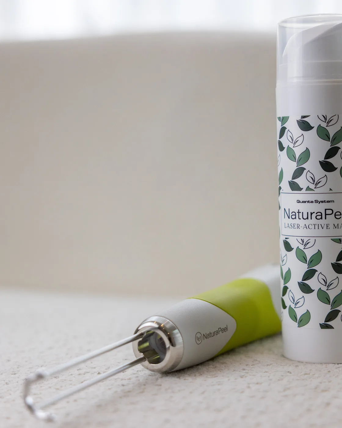 Masque laser-actif NaturaPeel et sa pièce à main posés sur une surface claire